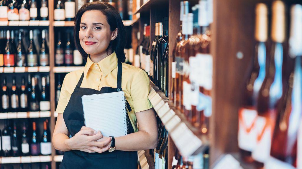 Woman Standing in Front of Shelves of Wine and Liquor