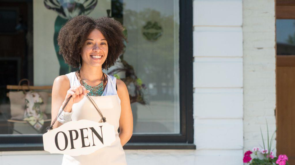 Woman Business Owner in Front of Building with Open Sign