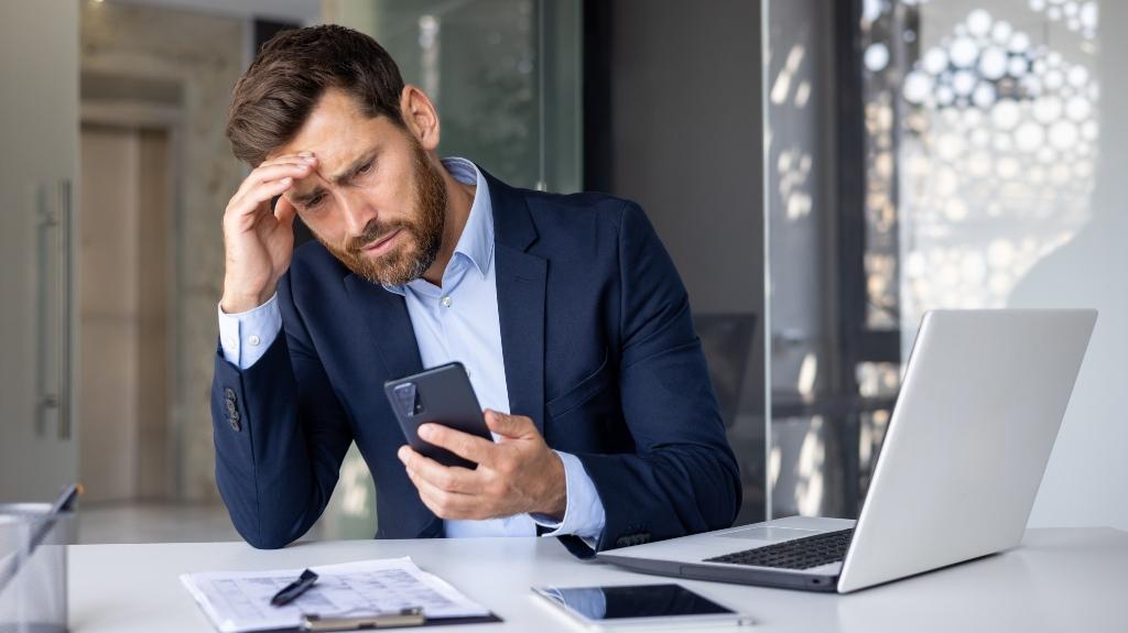 Shocked businessman sitting holding hand to head