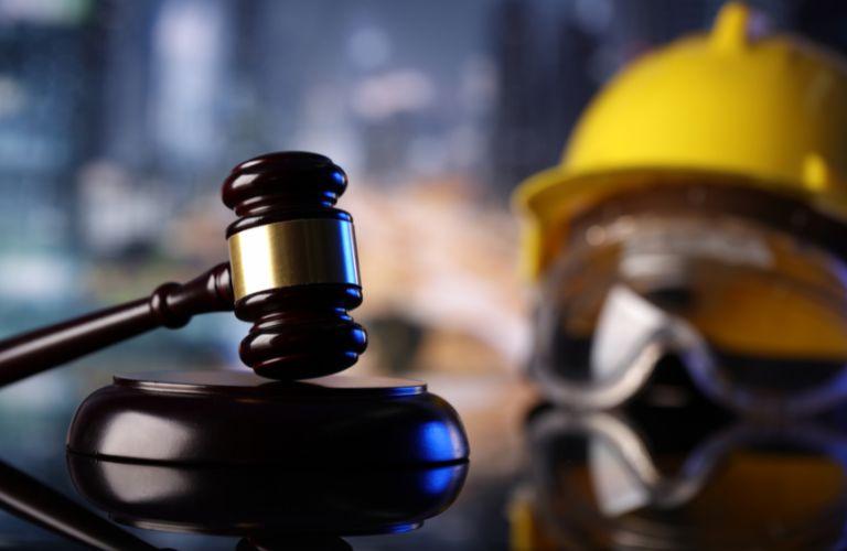 Yellow Hardhat, Safety Glasses and a Gavel on a Desk