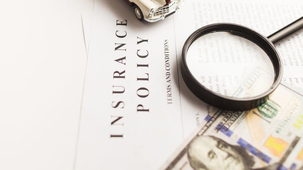 Life Insurance Policy Documents with Magnifying Glass and Cash on a Table