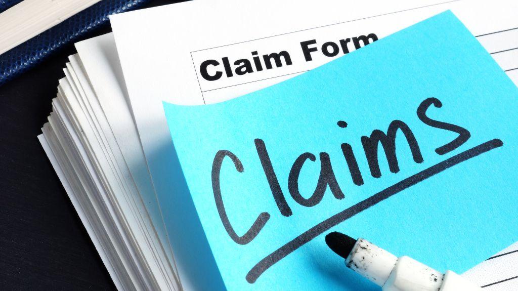 Insurance Claim Form with Blue Sticky Note with Claims in Marker
