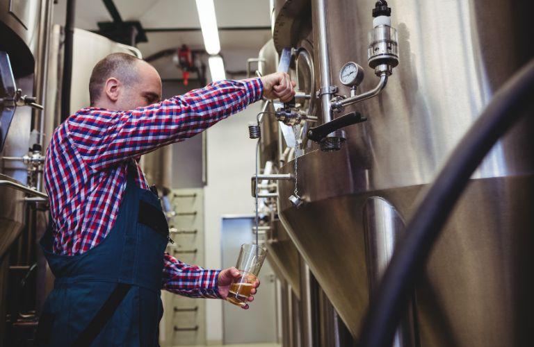 Brewer Taking a Sample of Beer from a Mash Tun