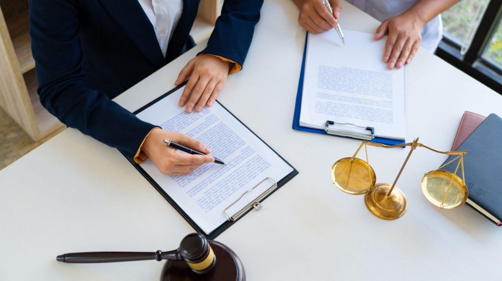 Attorney Doing Paperwork with a Client at a Desk